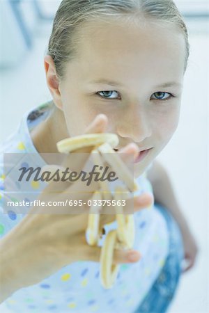 Girl holding biscuits ronds sur les doigts, en regardant la caméra