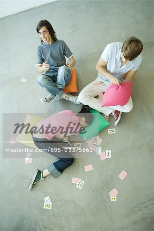 Adolescents amis avec des cartes à jouer éparpillées autour d'eux, haute angle vue