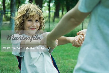 Boy holding hands with mother, partial view