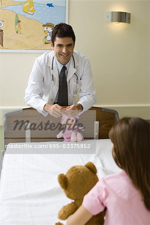 Doctor smiling at little girl, holding doll