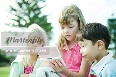 Children on playground, playing video game