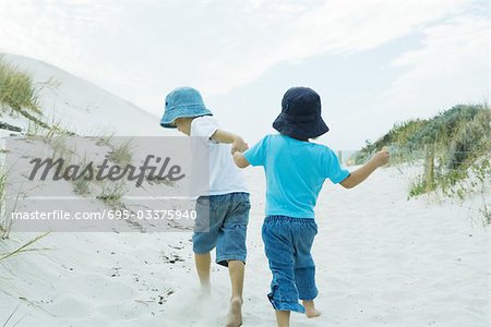 Children running through dunes, holding hands