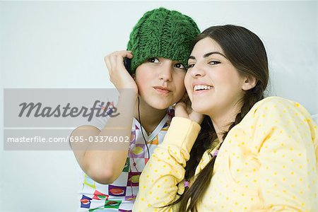 Two young female friends listening to headphones