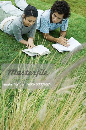 Young couple lying on grass reading books