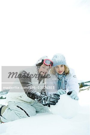 Deux adolescentes, accroupi dans la neige, Bâtissons ensemble, boule de neige, un sourire à la caméra