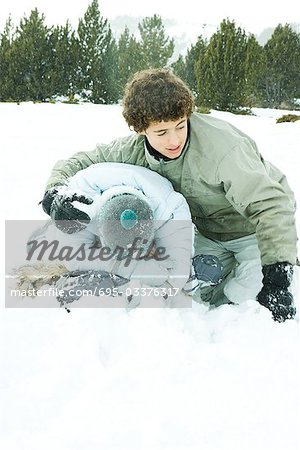 Two young friends crouching in snow, male's arm around female's shoulder, female's head down