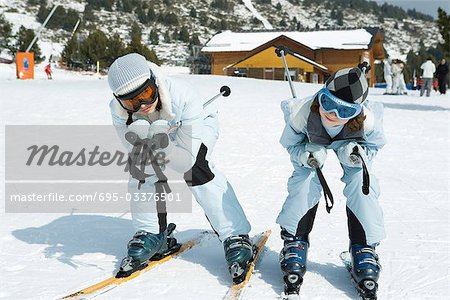 Two young skiers crouching together, looking at camera