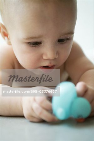 Baby lying on floor, holding toy, close-up