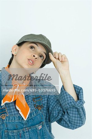 Teenage girl adjusting cap, looking up, portrait
