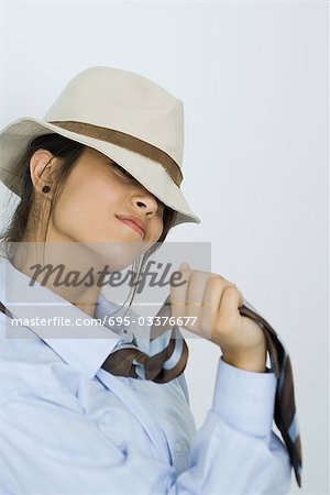 Teenage girl wearing tie and hat, smiling at camera, portrait