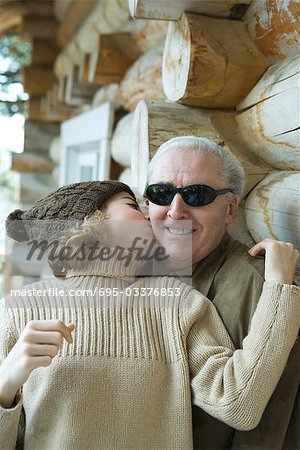 Teenage girl kissing grandfather on the cheek, portrait