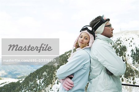 Deux jeunes skieurs debout dos à dos, souriant, un appareil photo, en regardant portrait