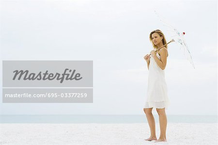 Frau stehen an der Strand-Sonnenschirm Betrieb, Wegsehen