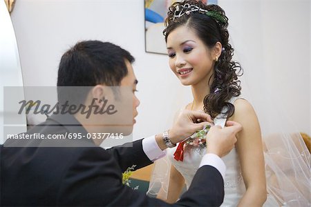 Groom pinning corsage on bride's dress