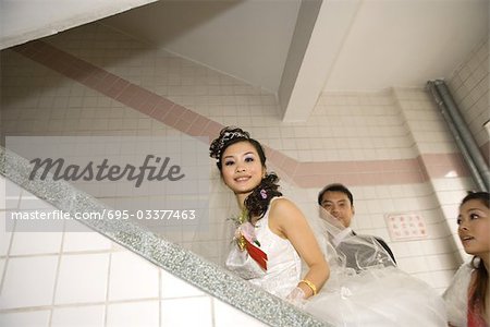 Bride, groom and bridesmaid walking up stairs