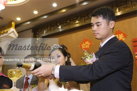 Bride and groom pouring champagne together at reception