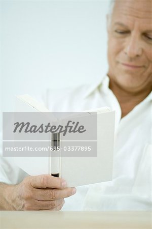 Mature man reading book, cropped view