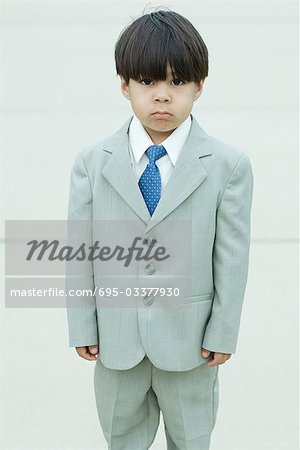 Young boy dressed in suit, frowning at camera