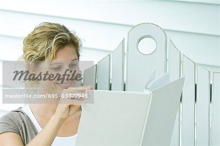 Woman on bench reading book, smiling, close-up