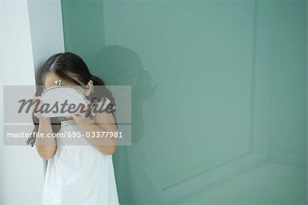 Little girl hiding face behind coin purse