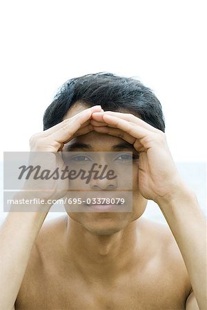 Man shading eyes, looking at camera, portrait