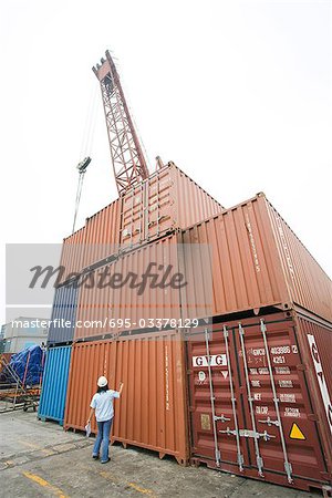 Femme debout devant les unités de stockage industriel empilées, vue arrière