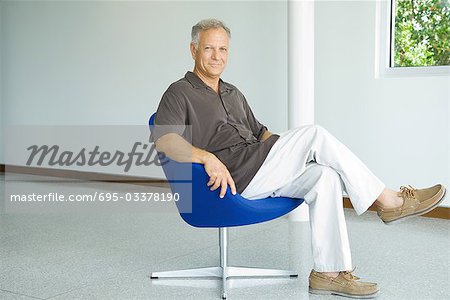 Mature man sitting in chair, full length, portrait