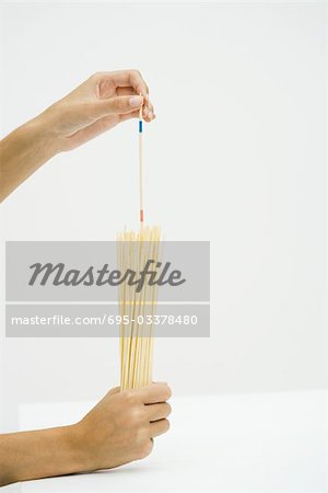 Hands holding dried pasta, measuring with stick