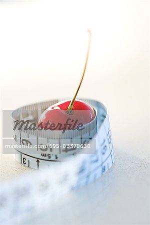 Measuring tape wrapped around cherry, close-up
