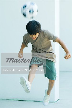 Kleiner Junge spielt mit Fußball, springen, Kopf nach unten