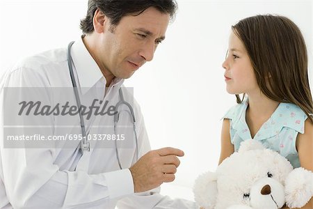 Médecin assis avec la petite fille, fille tenue d'ours en peluche