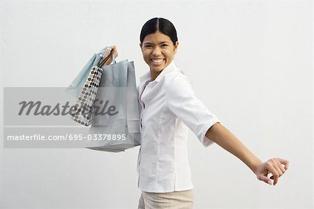 Jeune femme tenant des sacs à provisions, souriant à la caméra