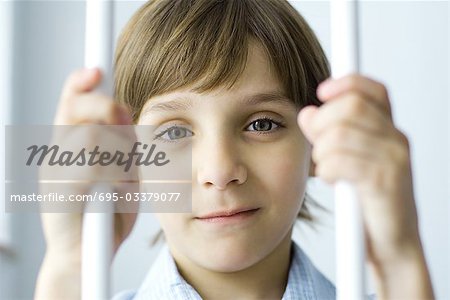 Boy behind bars, smiling at camera, portrait