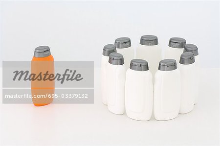 Group of white bottles in circle and single orange bottle