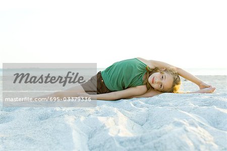 Girl stretching on beach, full length