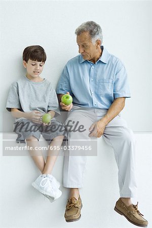 Grand-père et petit-fils, assis sur la corniche, les deux pommes holding