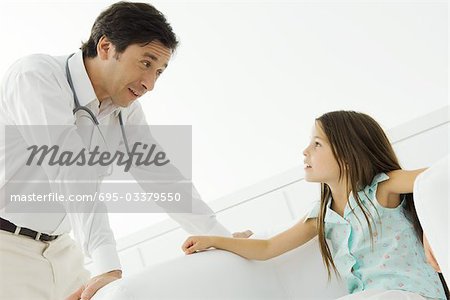 Doctor leaning over, talking with little girl
