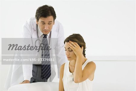 Woman holding head, doctor leaning behind her
