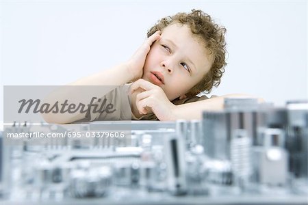 Little boy next to circuit board, holding head, looking up