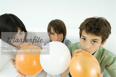 Mutter und zwei Söhne aufblasen Luftballons, jungen Blick in die Kamera