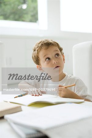 Kleiner Junge sitzt vor den Hausaufgaben, nachschlagen