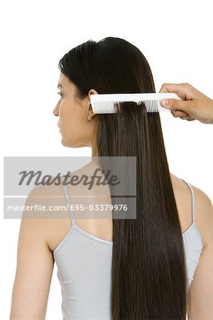 Woman having her long hair combed, rear view