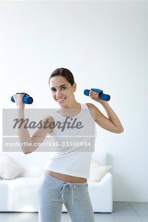 Teen girl lifting dumbbells, smiling at camera