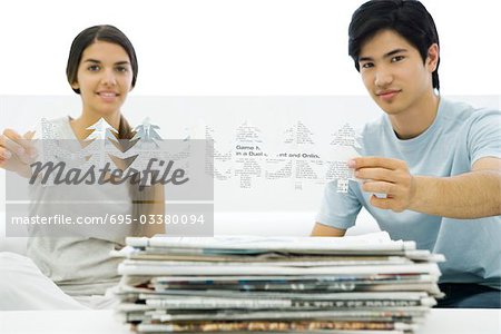 Zwei junge Erwachsene halten Baum Formen geschnitten aus Zeitung, lächelnd in die Kamera
