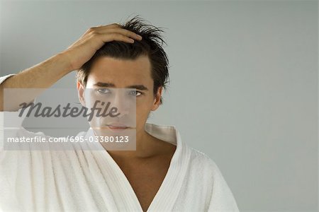 Man looking at self in mirror, hand in hair