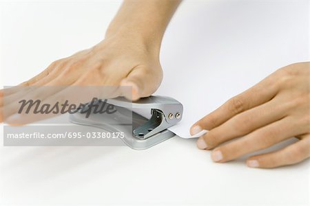 Hands using hole puncher