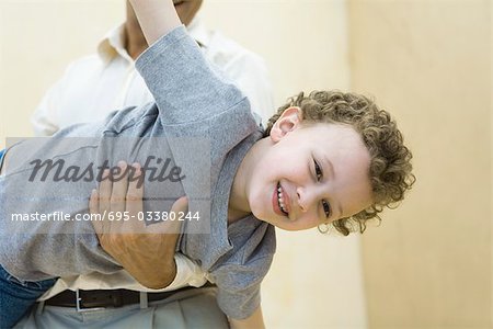 Boy pretending to be a plane, being held by his father