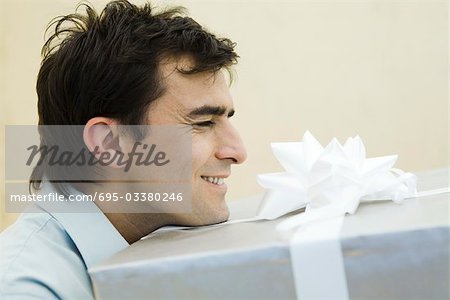 Homme transportant grand présent, yeux fermés, côté vue