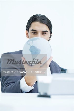 Young businessman holding globe and looking down at it