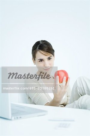 Young woman holding apple, looking down